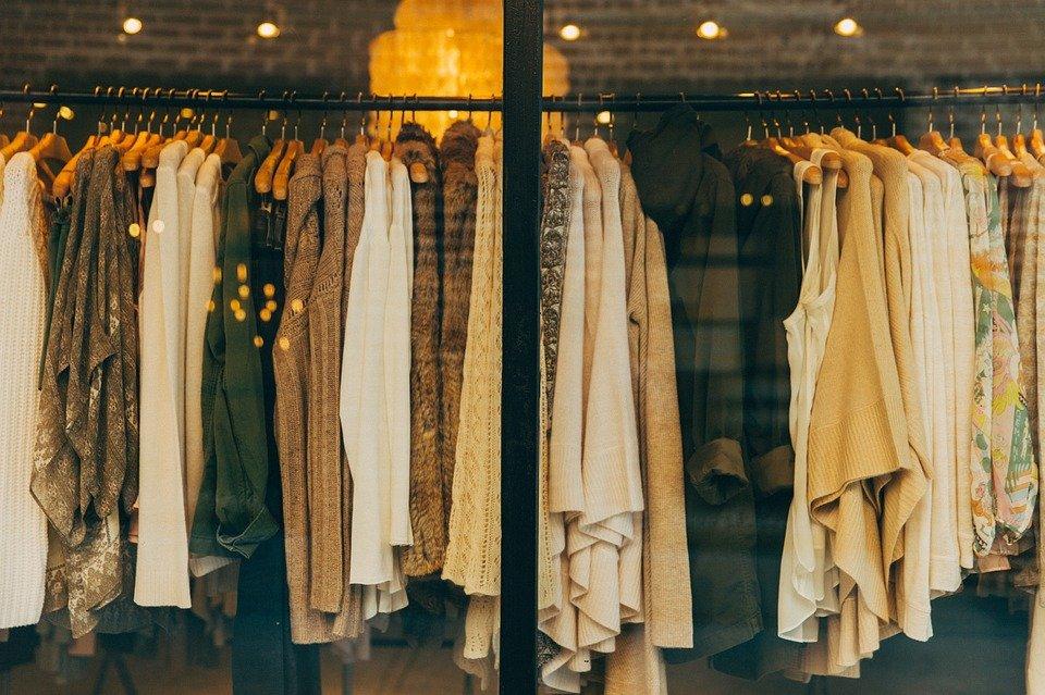 Clothing rack of sweaters and cardigans on wooden hangers in a shop window